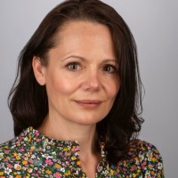 Woman (head and shoulders) side-parted brown shoulder length hair.