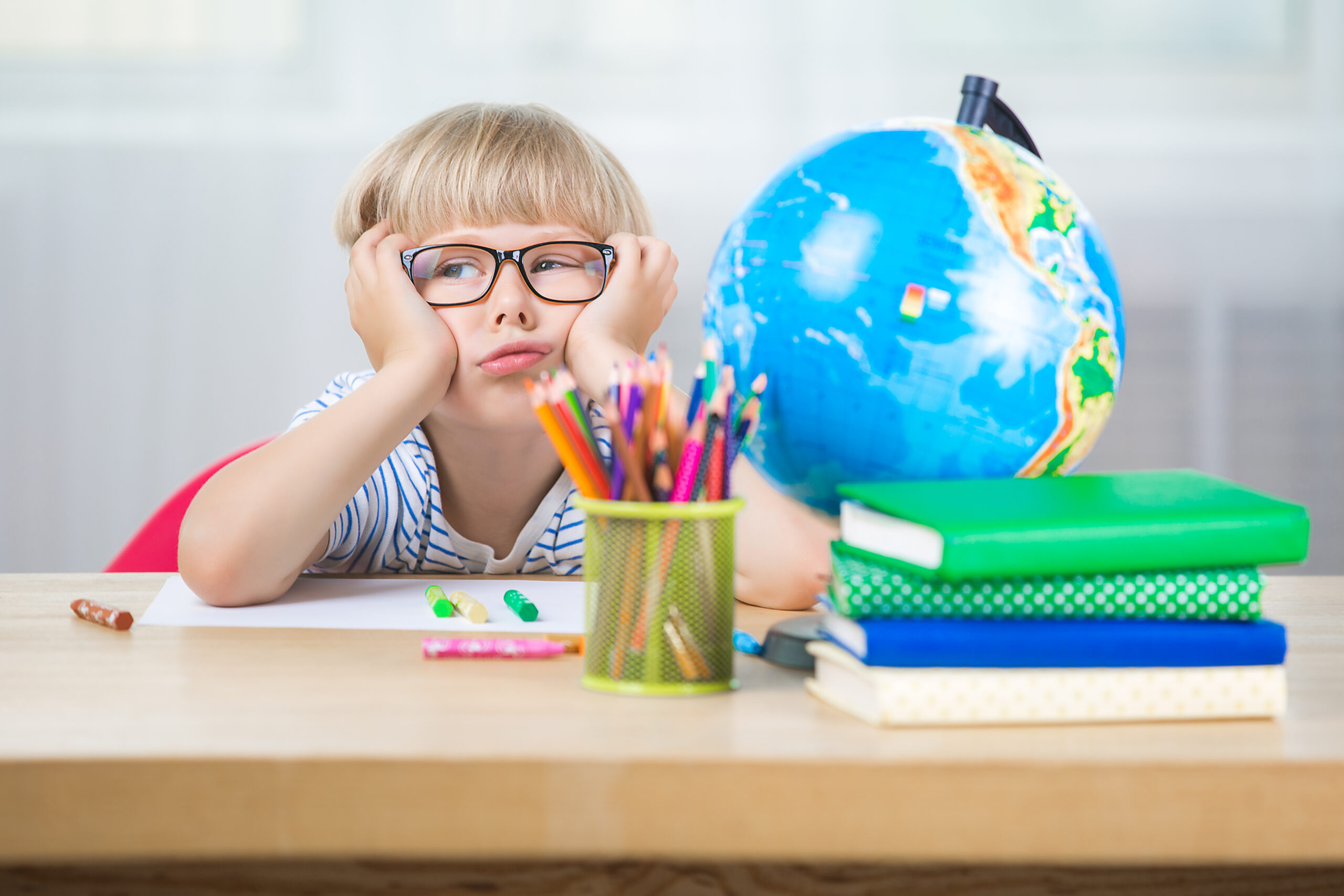 Cute child bored at a desk during a school lesson.