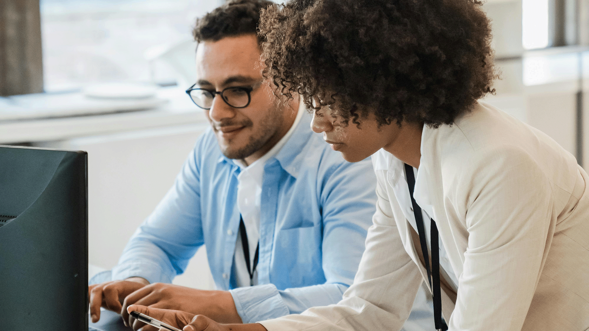 Man and woman at an office desk looking at an computer
