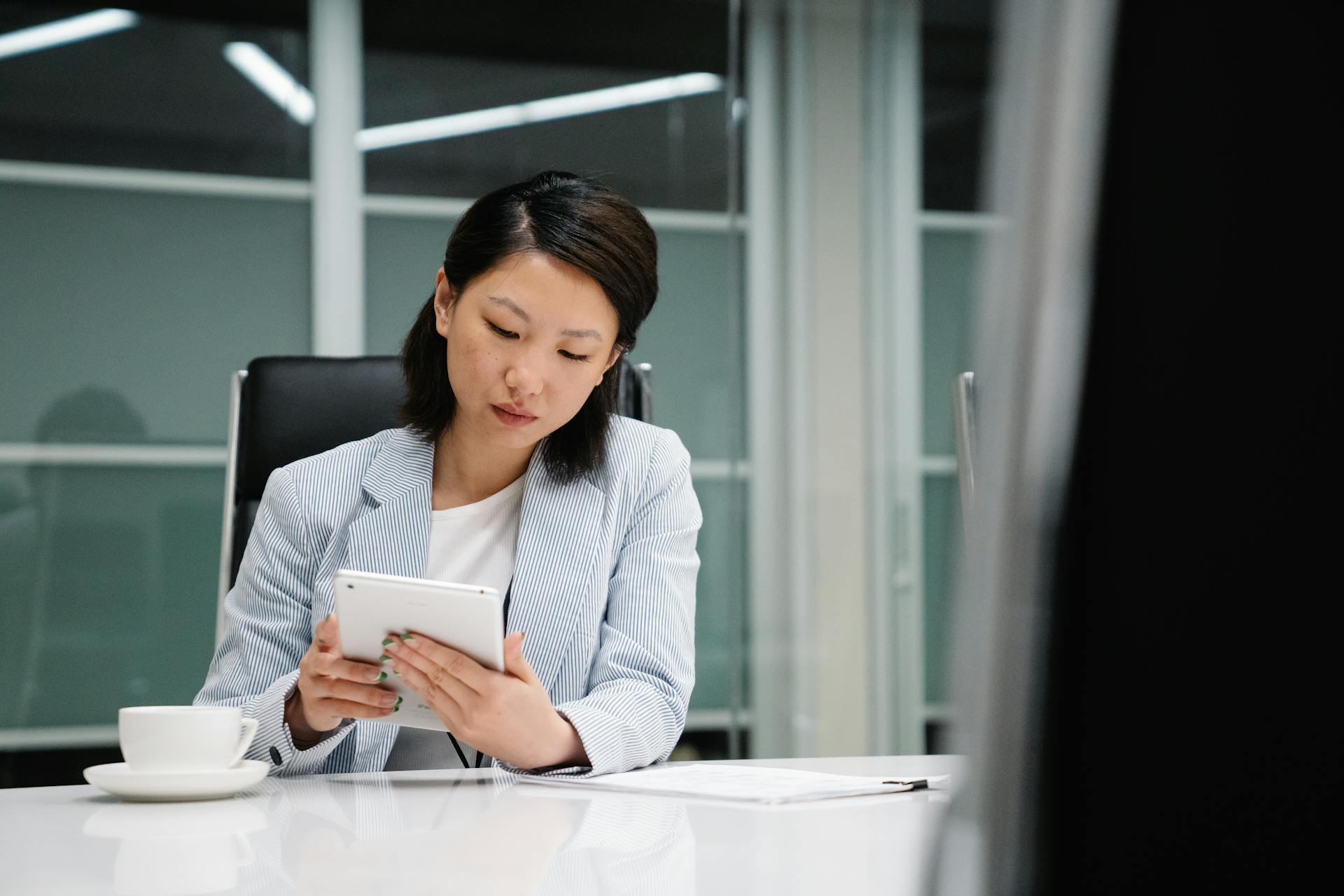 Businesswoman sitting by desk with tablet