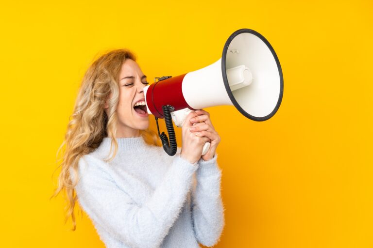 Blonde woman shouting into a megaphone.