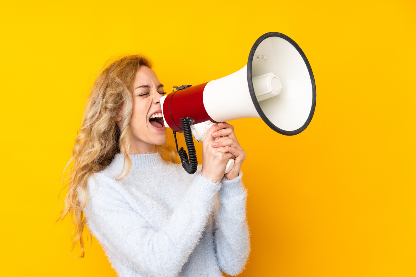 Blonde woman shouting into a megaphone.