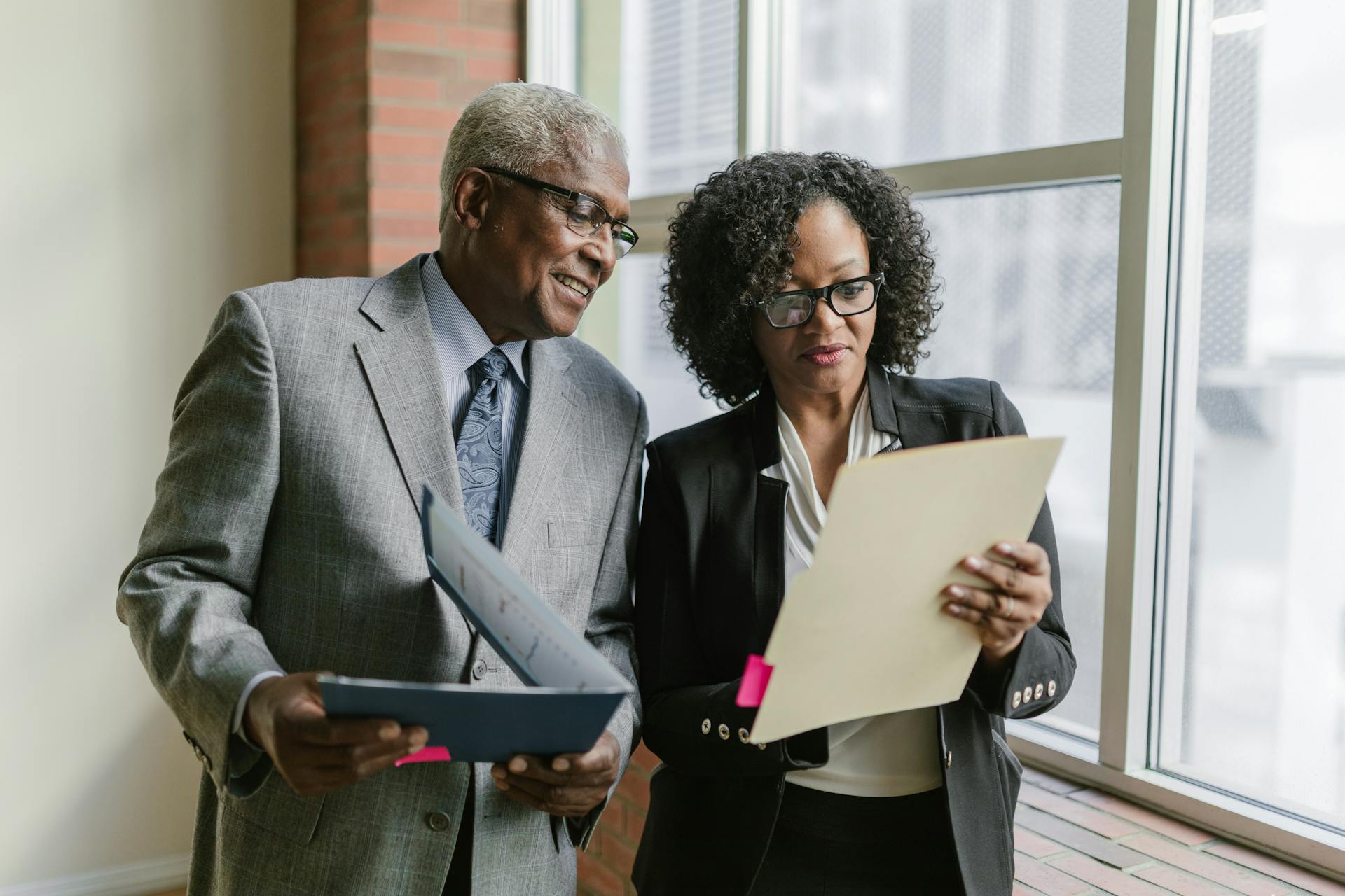 An Elderly Man and a Woman Looking at a Folder while Having a Conversation
