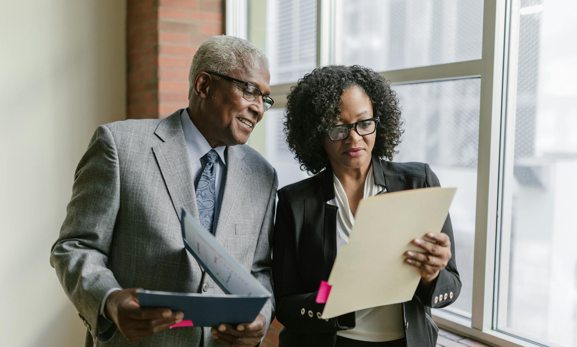 An Elderly Man and a Woman Looking at a Folder while Having a Conversation